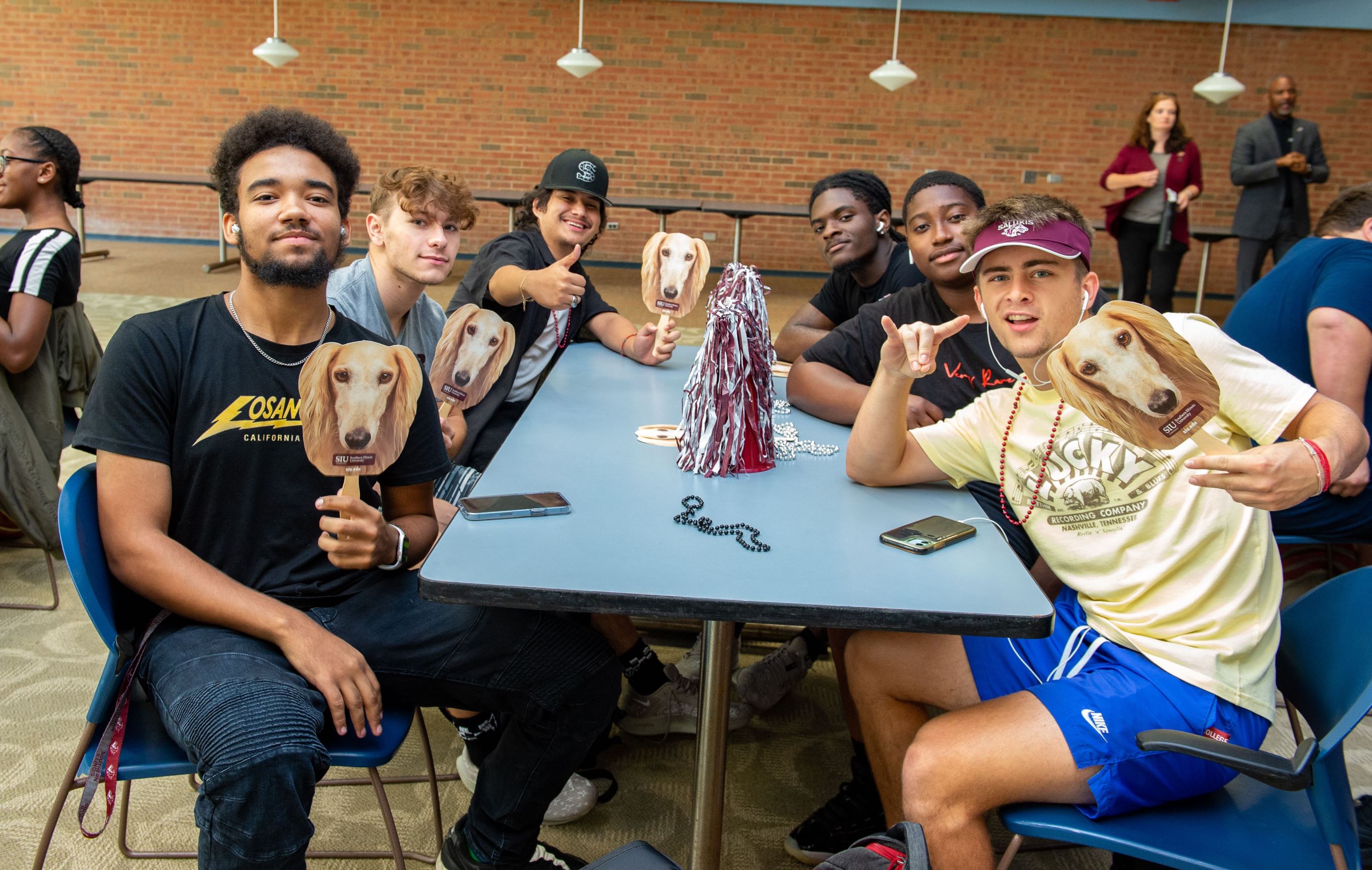 table of six guys holding up saluki dog signs